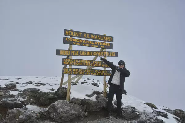 Climber on the summit during the 6-day Kilimanjaro climbing tour package via the Machame route